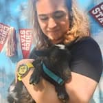 Bailey Myles holding a baby goat in front of Chico State pennants