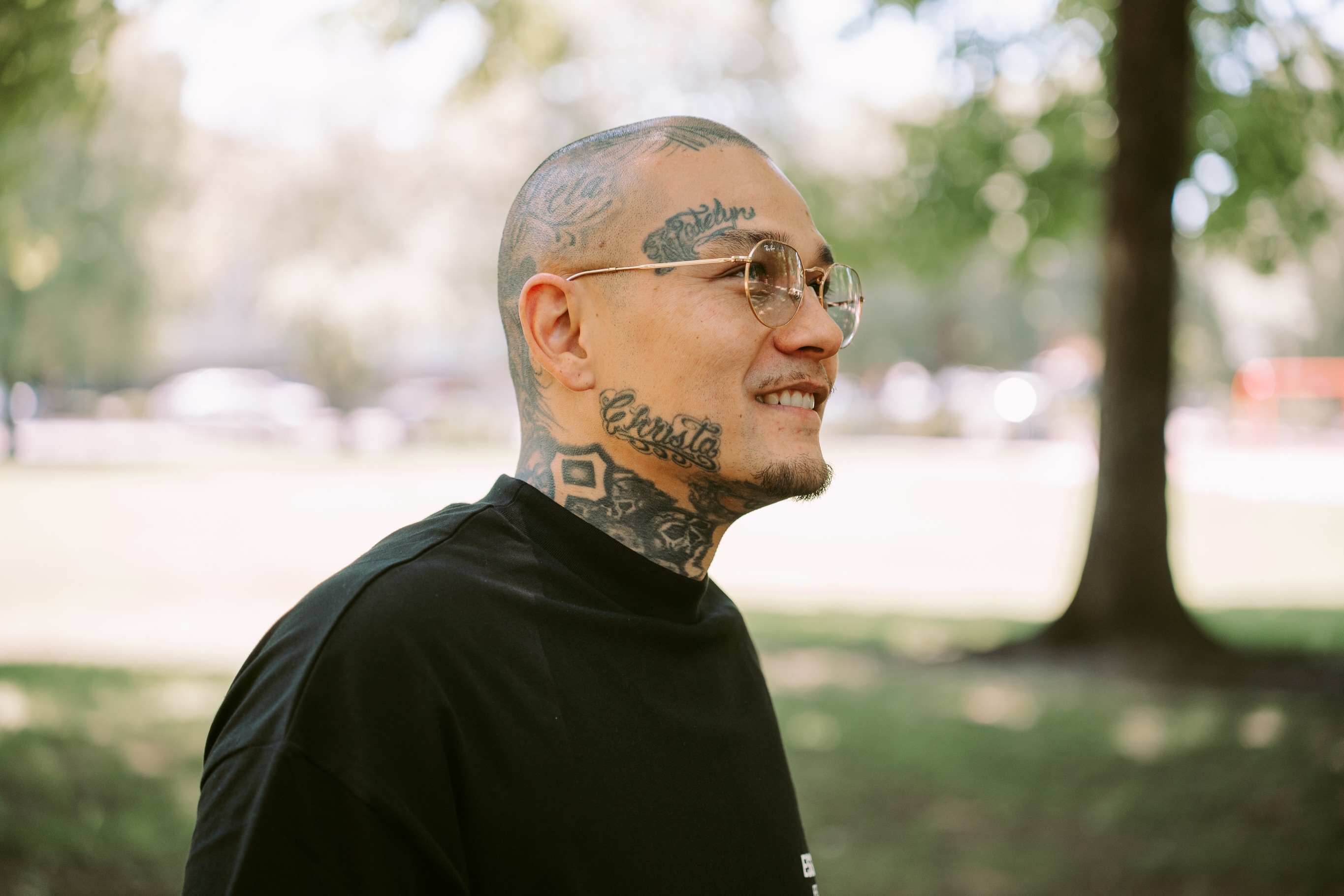 Close portrait of the tattooed subject smiling in soft park light